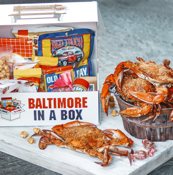 A Baltimore in a Box gift box beside a tray of steamed crabs